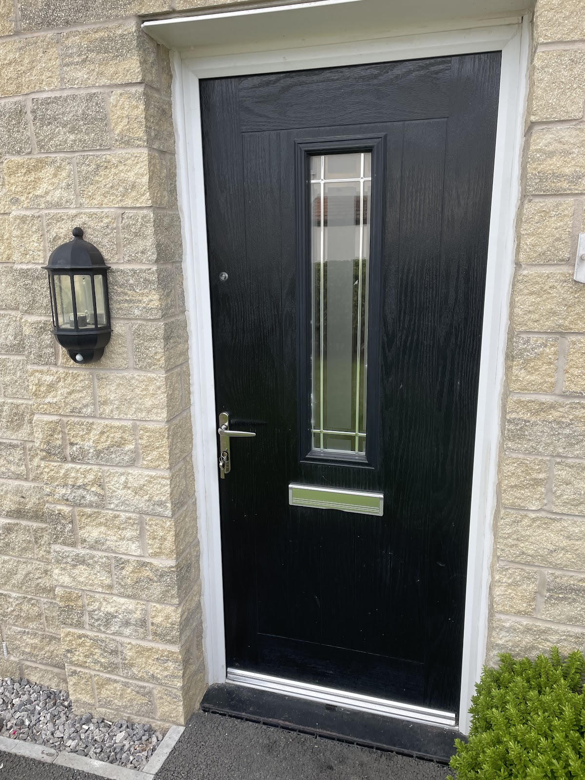 Black composite front door with chrome handle, fitted in Manchester