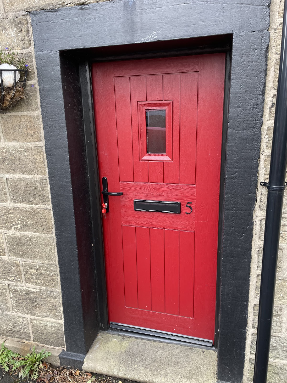 Red composite door in stone surround